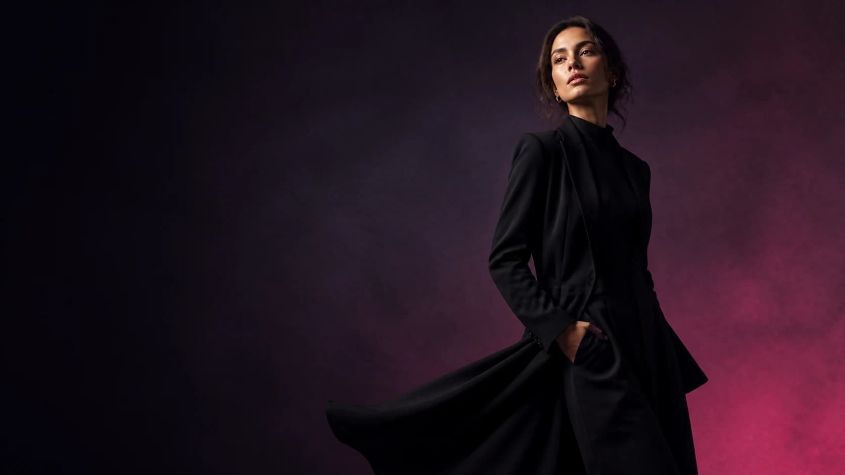 Fashion model in a dark purple studio wearing a black suit